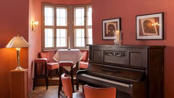 A cozy room with a piano, a table, and chairs.