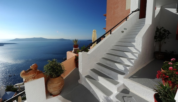 Una escalera conduce a un balcón con vistas panorámicas al mar y la costa lejana.