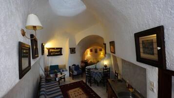 Una habitación acogedora y estrecha con comedor, sofá y una zona de cocina con fregadero.