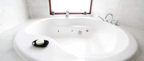 A modern bathroom with a freestanding bathtub, a window above the tub, and a marble floor.