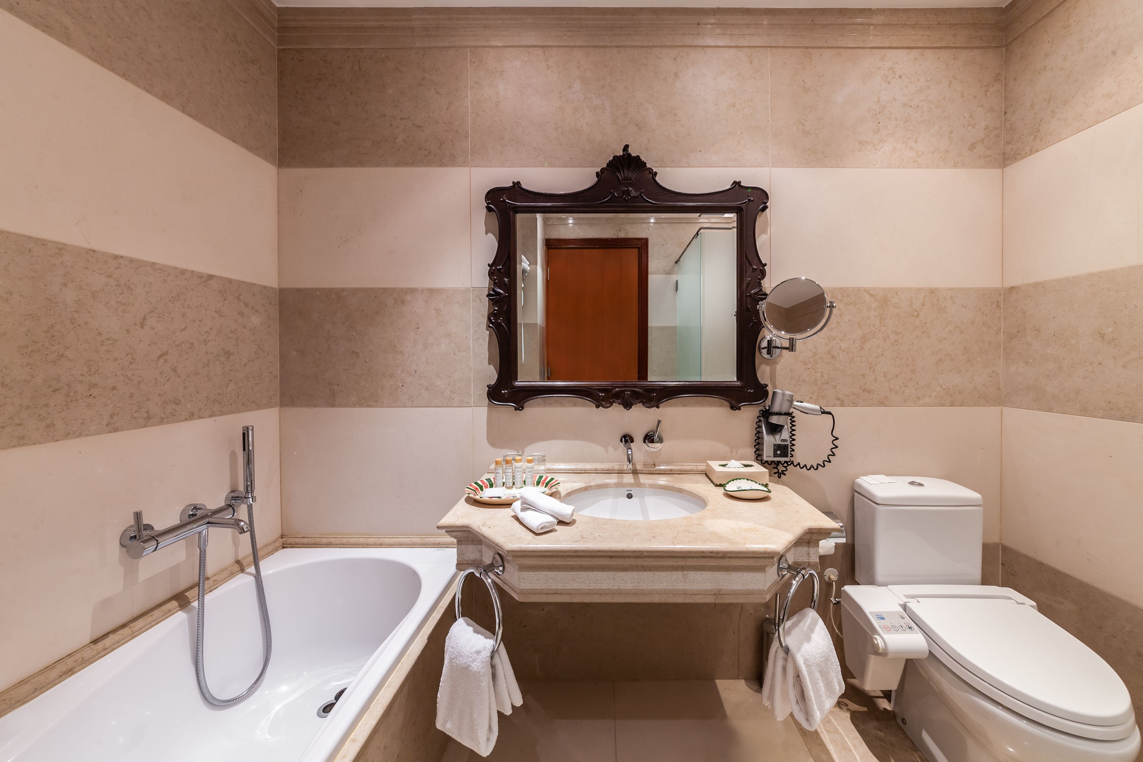 Un baño con bañera, lavabo, inodoro y un espejo grande.