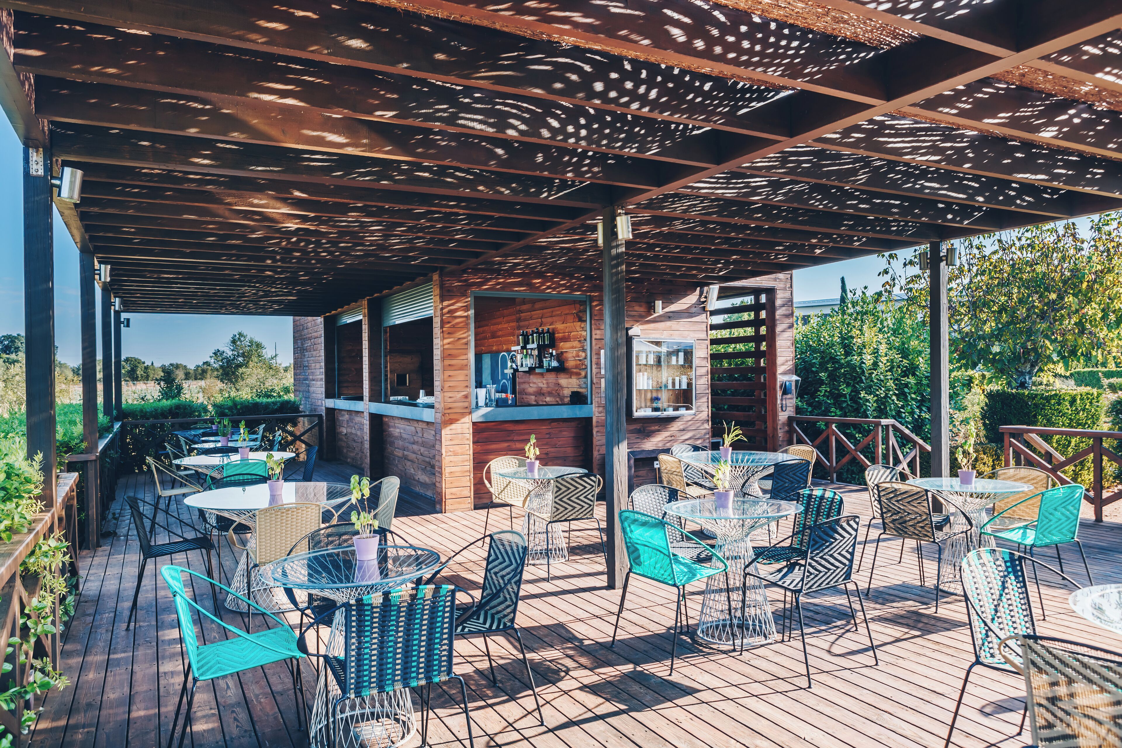 Un patio al aire libre con mesas y sillas, un muro de ladrillo y una estructura de pérgola.