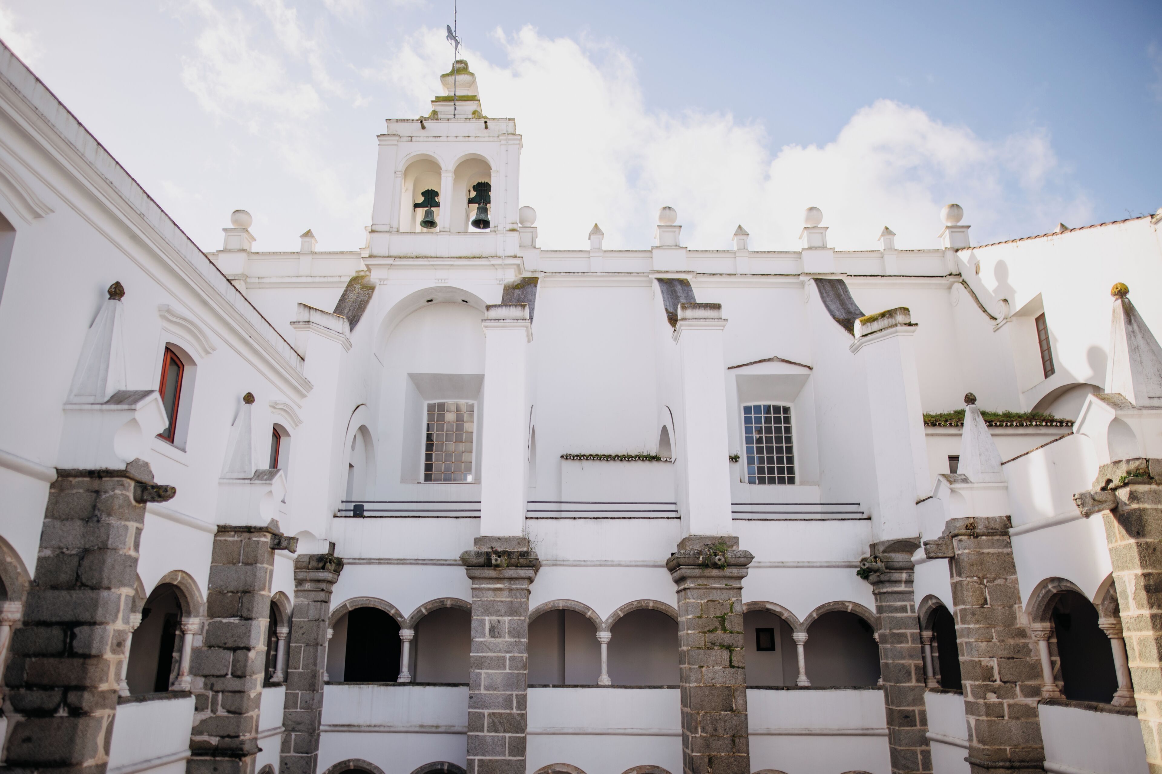 A historical building with white walls, multiple arches, and a bell tower.
