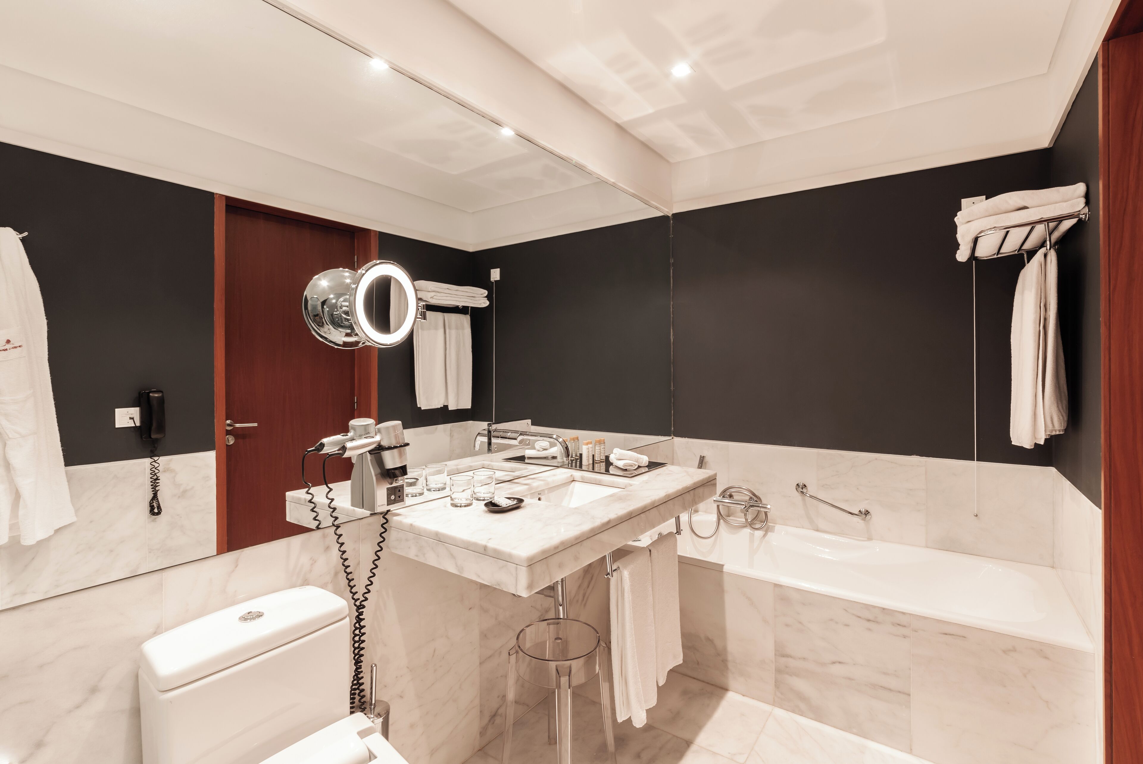 Un baño moderno con un espejo grande, una bañera, un inodoro y un lavabo con mueble.