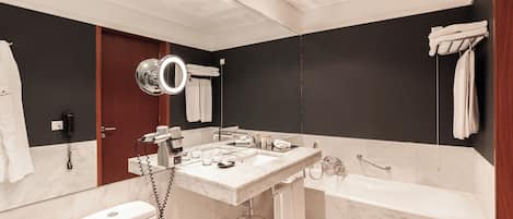 Un baño moderno con un espejo grande, una bañera, un inodoro y un lavabo con mueble.
