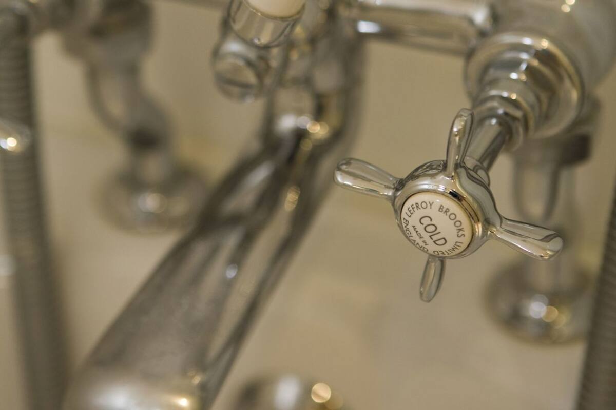 A shower with a white handle labeled 'SHOWER BATH' and a faucet with a 'COLD' label.