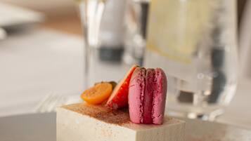 Ein Dessert mit Macarons und Früchten auf einem Teller, dazu ein Glas Weißwein.