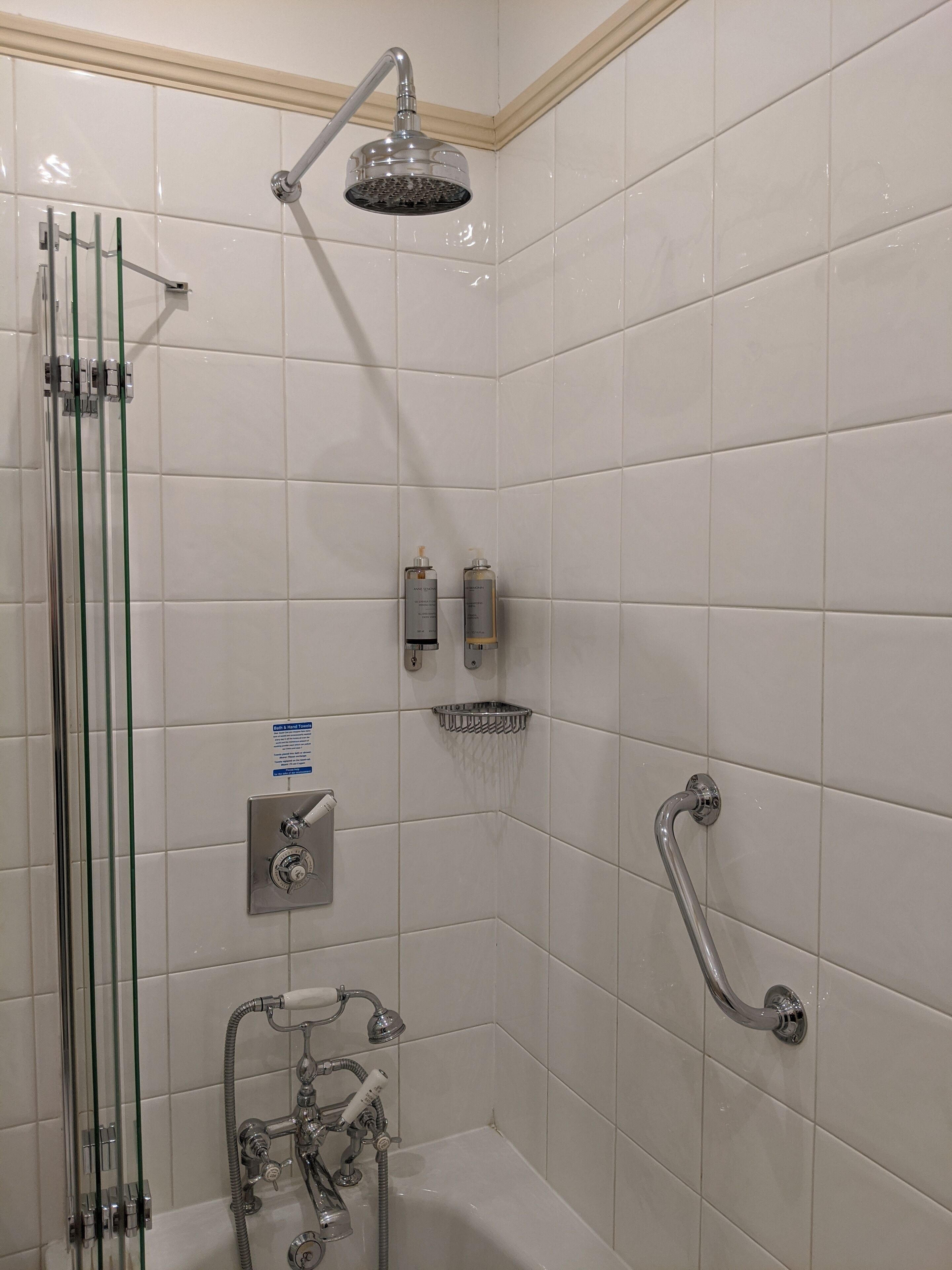 Un baño moderno con ducha envuelta en vidrio, cabezal de ducha manual y bañera.