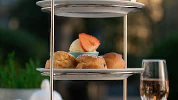 A three-tiered dessert stand with various pastries and a glass of champagne.