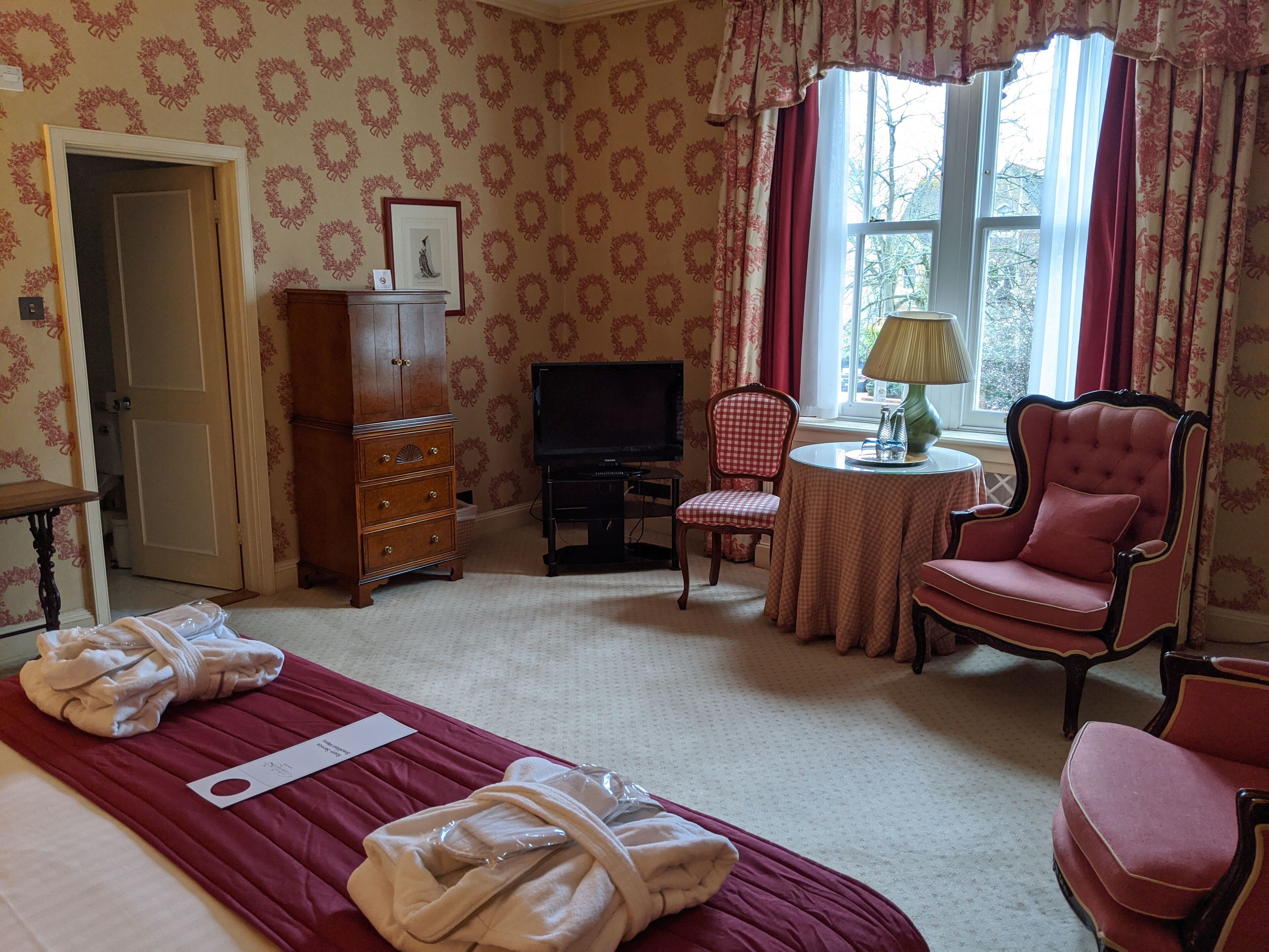 Ein Hotelzimmer mit Bett, Fernseher, Sessel, Tisch und Kleiderschrank.
