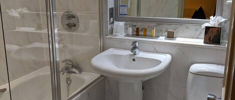 Ein Badezimmer mit Duschkabine, Waschbecken auf Säule und Toilette.