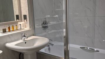 Een moderne badkamer met een douchecabine van glas, een wastafel op een voetstuk en een toilet.