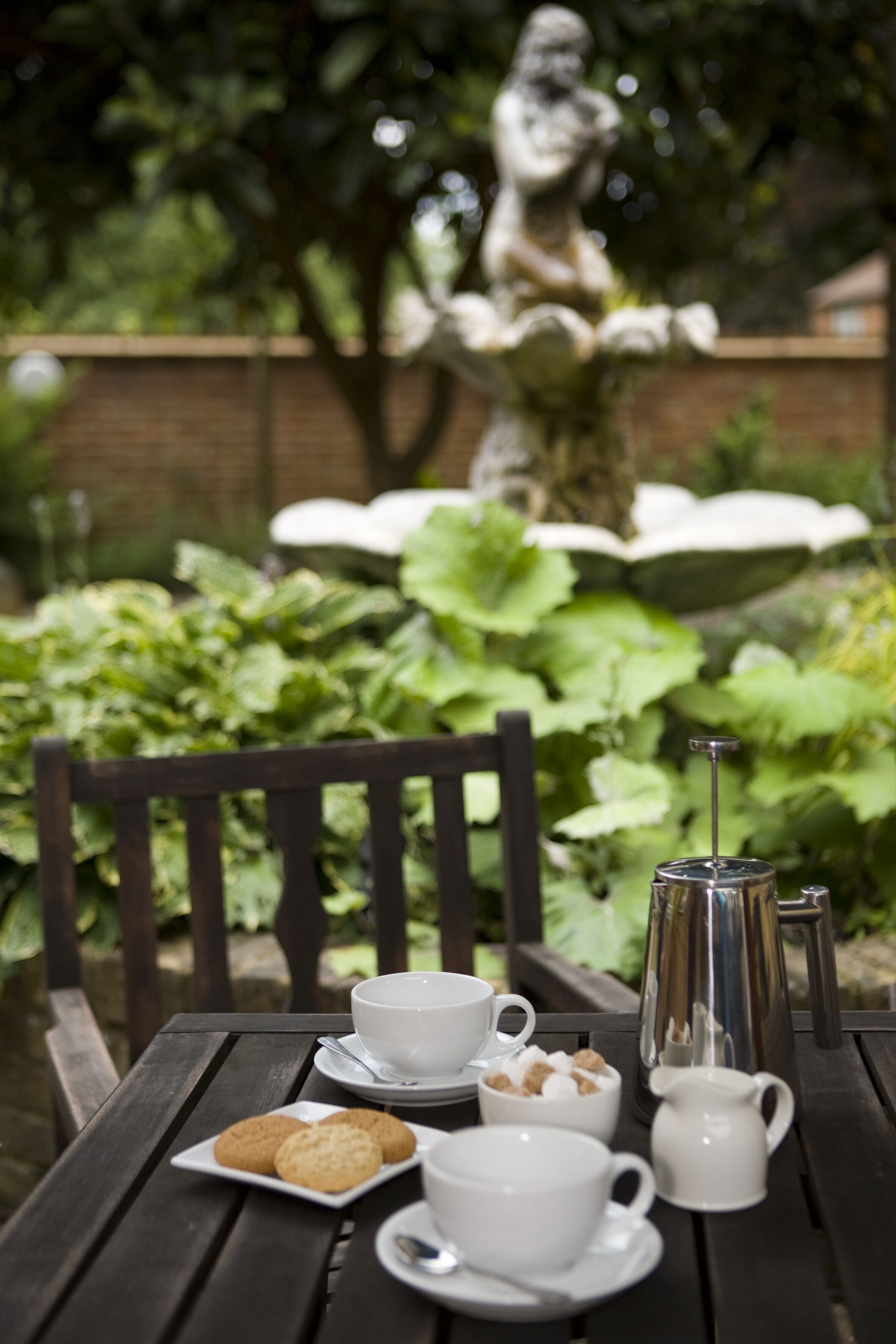 Une table en bois, dressée avec des tasses blanches, une théière et des biscuits.