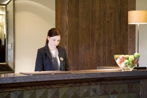 A reception desk with a name tag, a laptop, and a bowl of fruit. - Western House Hotel (Ayr)