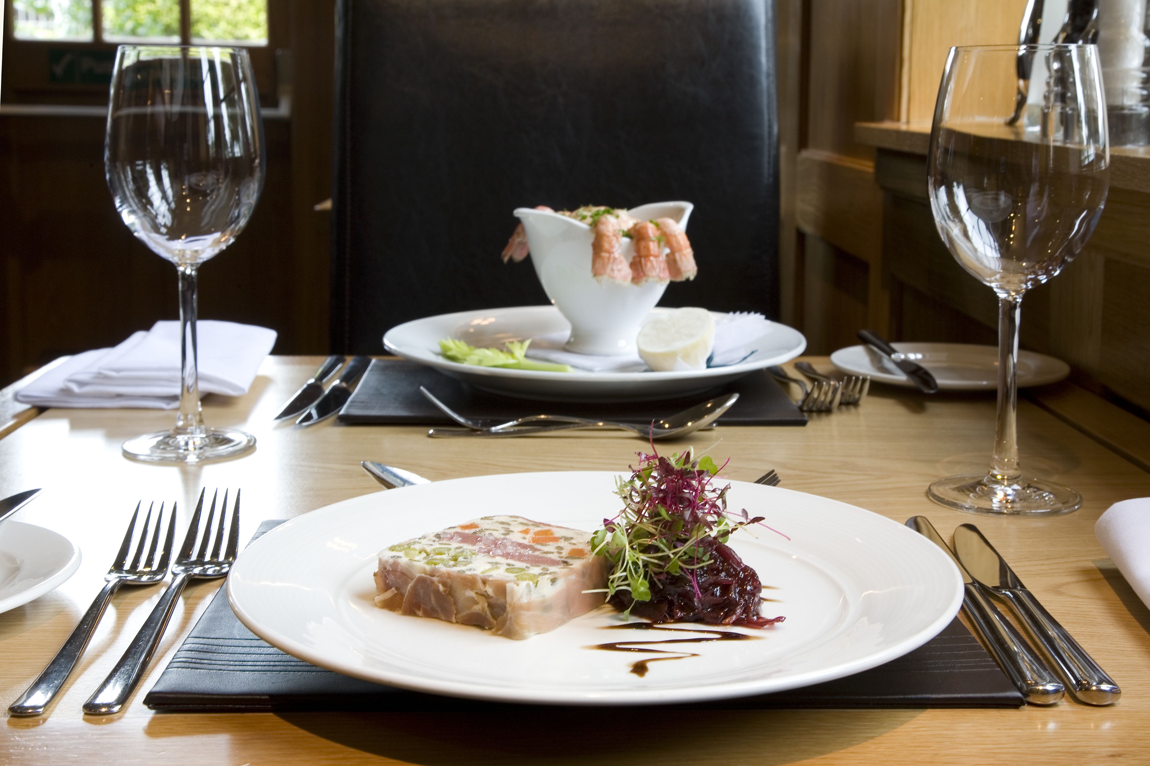 A dining table with a plate of food, a glass of water, and a bowl of shrimp.