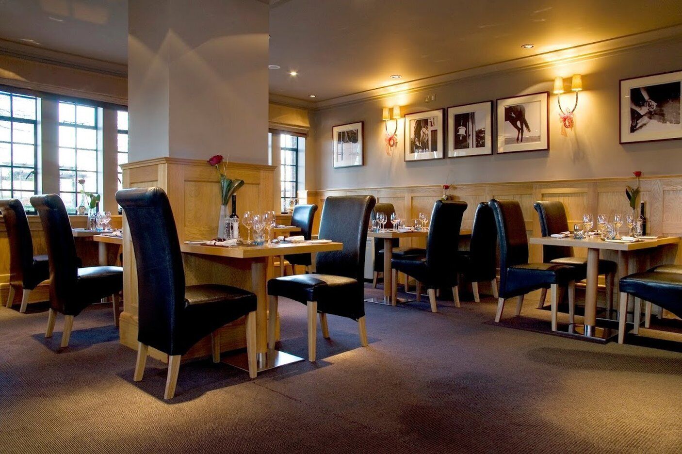 Ein Restaurant mit mehreren Tischen und Stühlen, gerahmten Bildern an der Wand und einem Teppichboden.