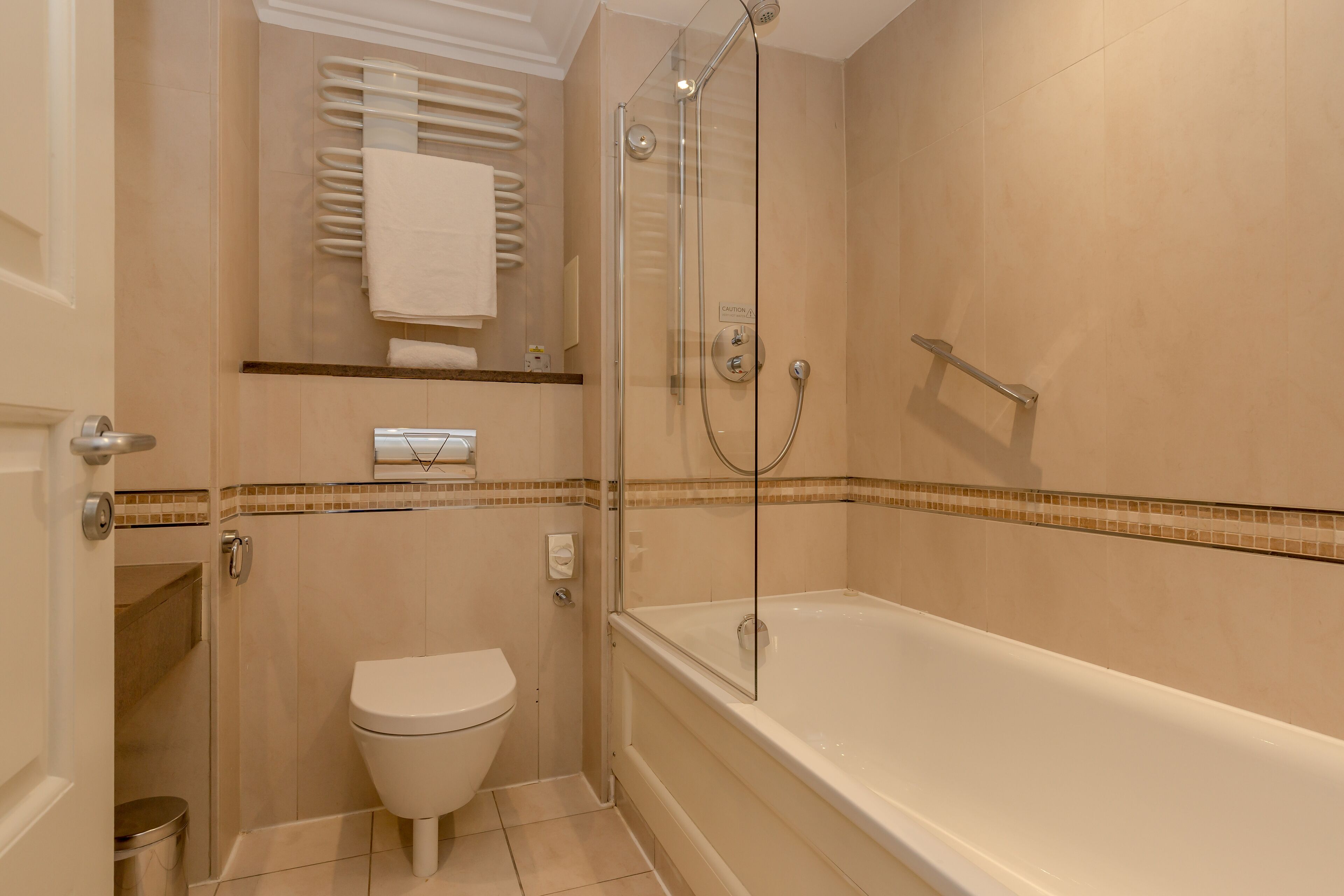A bathroom with a glass-enclosed shower, a white toilet, and a bathtub.