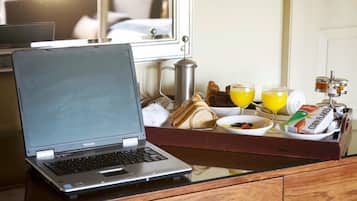 Una laptop Toshiba sobre una mesa de vidrio con alimentos para el desayuno, incluyendo pan, jugo y cereal.