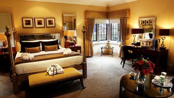 A hotel room with a large bed, a desk, a chair, a vanity with a mirror, and a window with curtains.