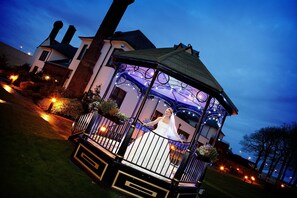 A gazebo with a glass roof, surrounded by a well-maintained garden and a large house in the background. - Western House Hotel (Ayr)