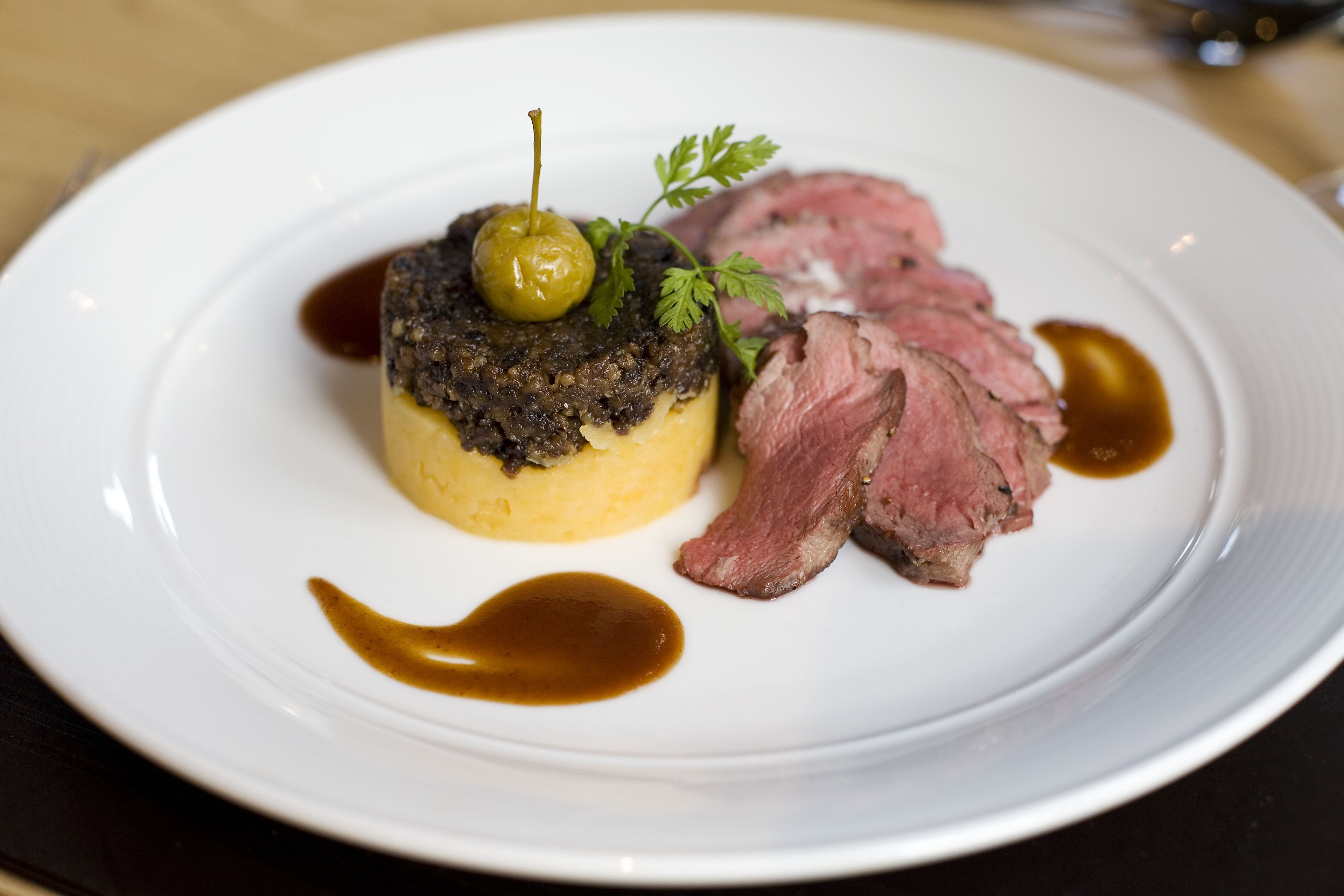 Une assiette contenant un plat de viande, une cuillerée de sauce et une garniture.