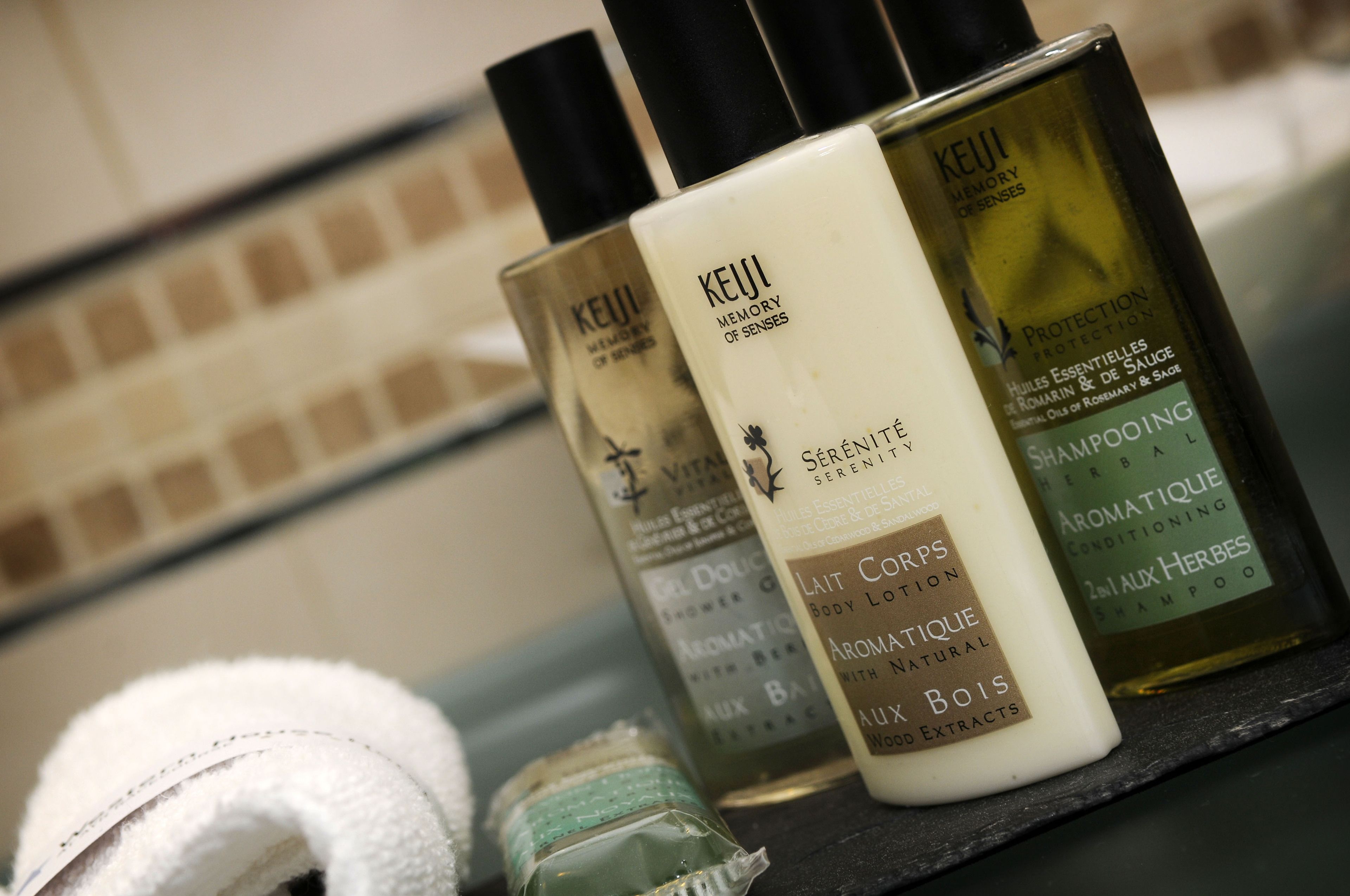 Uno scaffale in bagno con prodotti Keui, tra cui una lozione corpo, un gel doccia e uno shampoo.