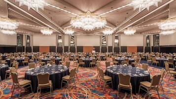 Une grande salle de banquet avec des tables rondes, des chaises et un tapis à motifs.