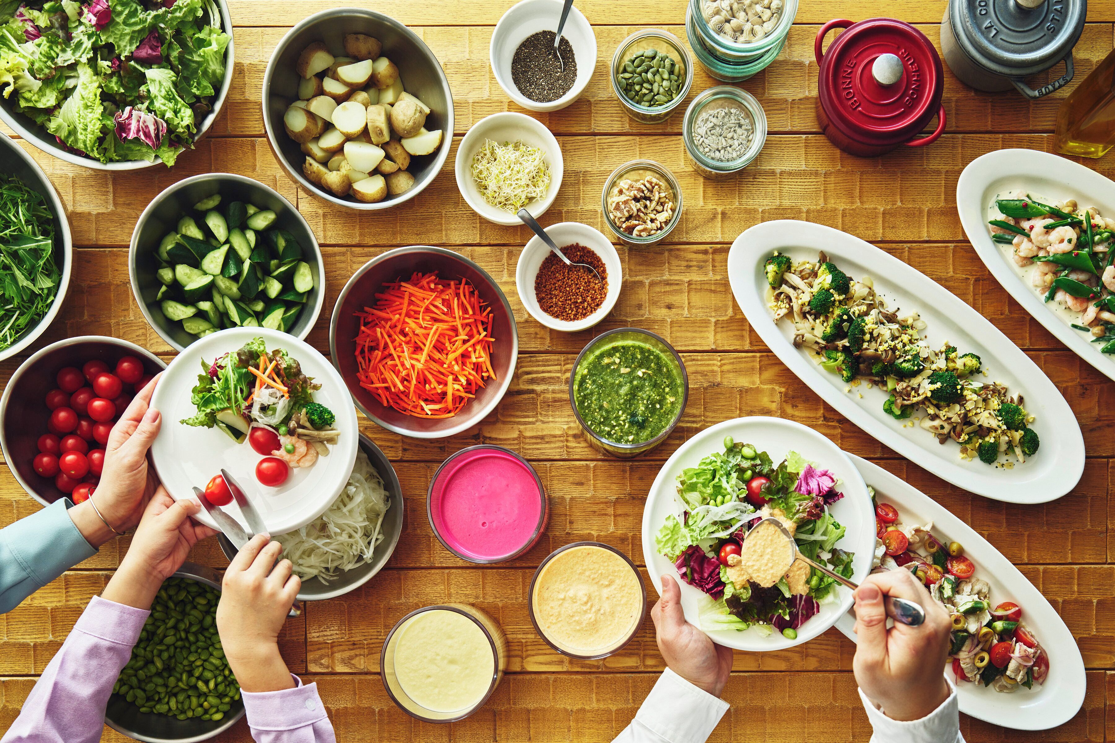 A variety of dishes and ingredients on a wooden table, suggesting a meal preparation or buffet setting.