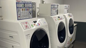 A row of white commercial washing machines with control panels, each featuring multiple buttons and instructions in a foreign language. - ANA Crowne Plaza Kobe by IHG (Kobe)