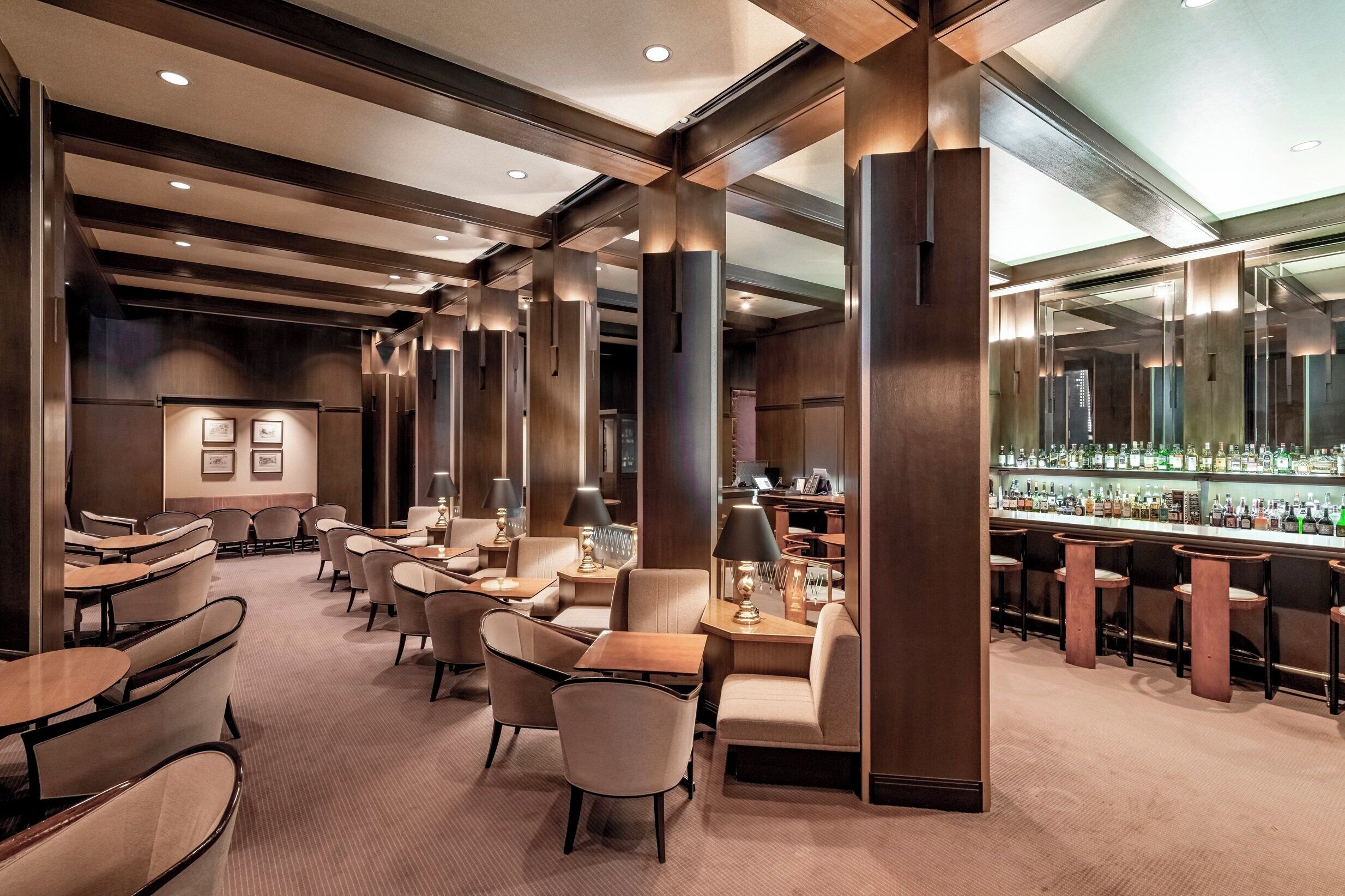 A hotel lobby with a bar area, seating arrangements, and a reception desk.