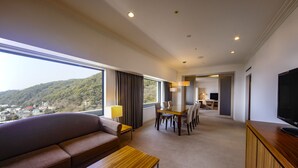 A hotel room with a large window, a sofa, a dining table, and a TV. - ANA Crowne Plaza Kobe by IHG (Kobe)