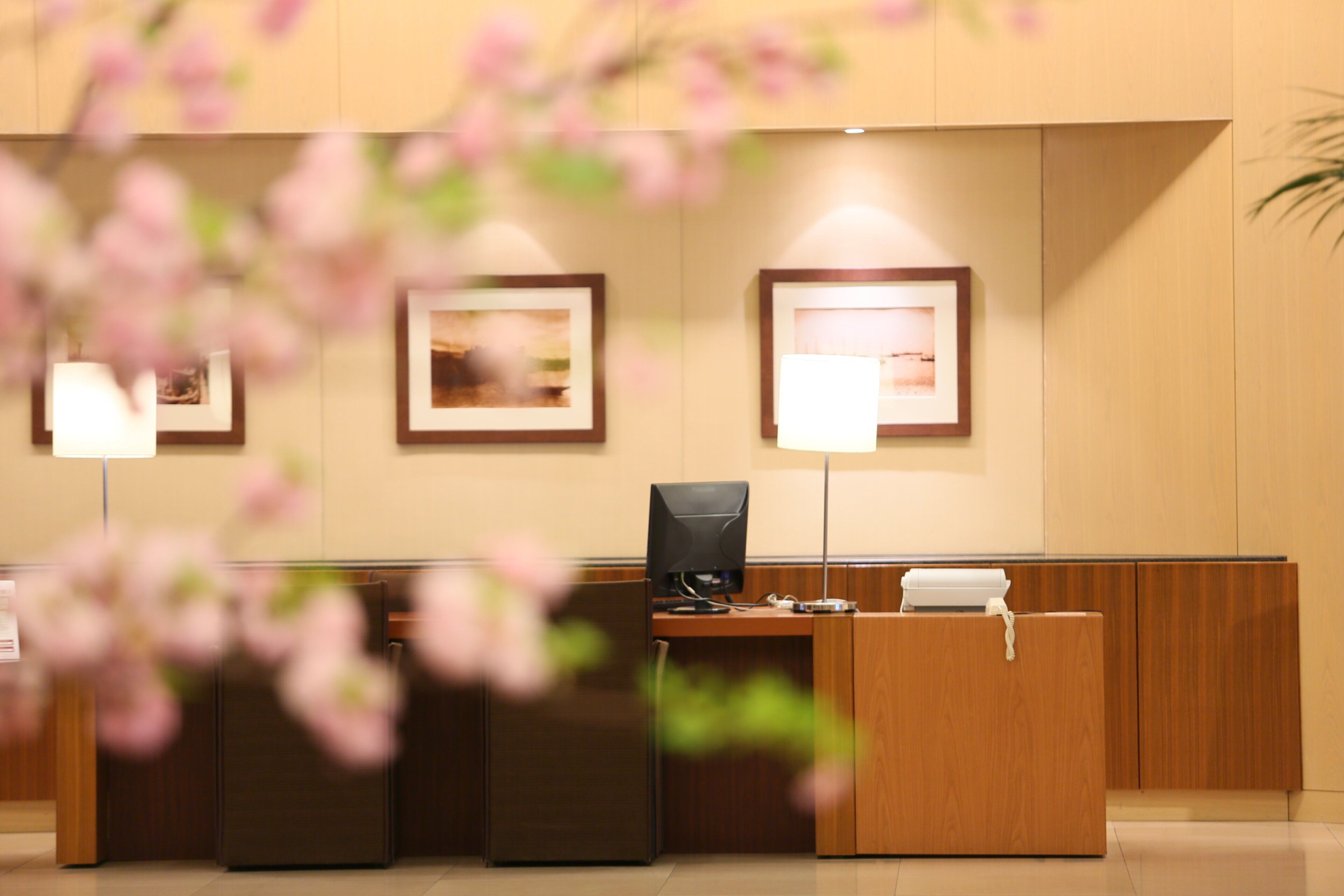A reception desk with a computer, a telephone, and framed pictures on the wall.