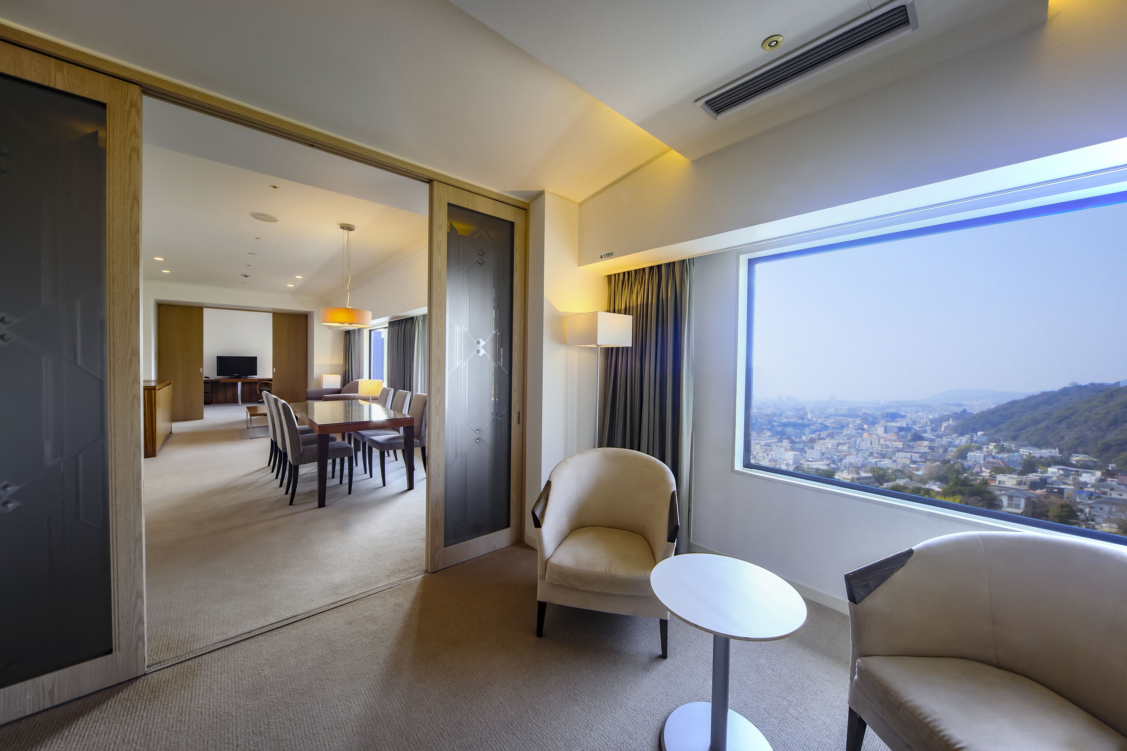 Una habitación de hotel con vista a la ciudad, zona de comedor y espacio de estar independiente.