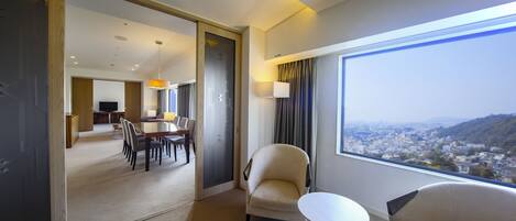 Una habitación de hotel con vista a la ciudad, zona de comedor y espacio de estar independiente.