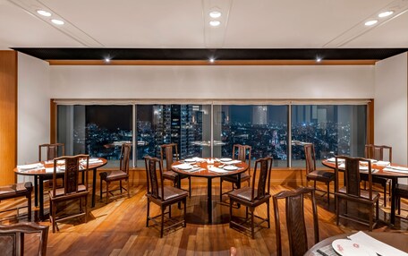 A dining area with a city view, wooden flooring, and modern lighting.