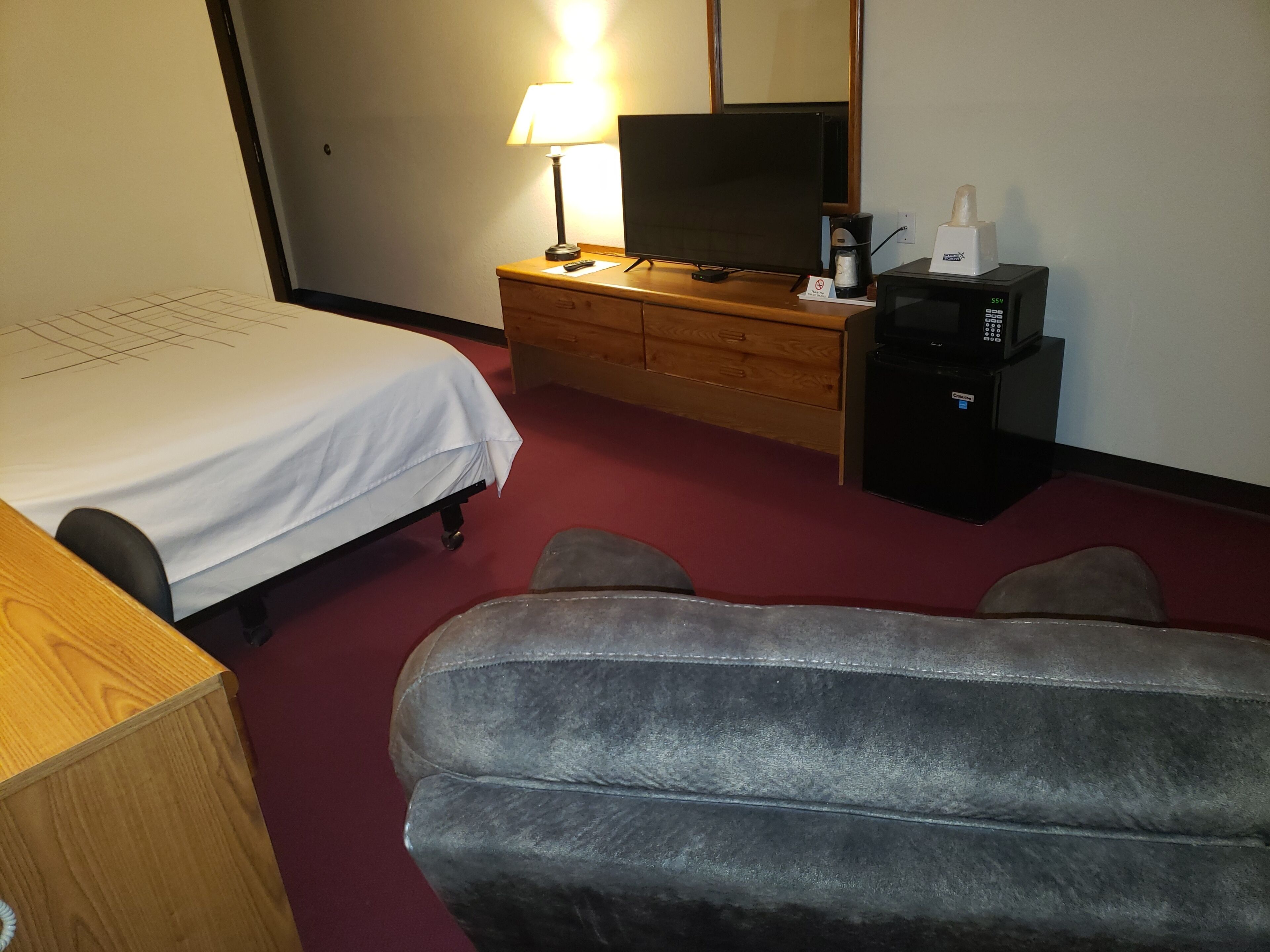 Habitación de hotel con cama, escritorio, televisor, cafetera y microondas.