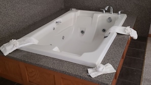 A corner bathroom with a freestanding bathtub, granite countertops, and dark tiled flooring. - Americas Best Value Inn & Suites International Falls (International Falls)