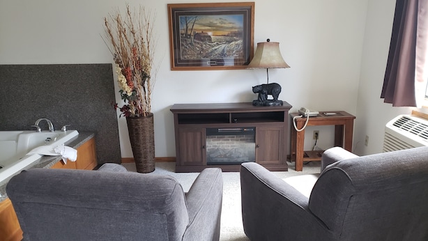 A living room with a sofa, a fireplace, a lamp, a painting, and a vase with branches. - Americas Best Value Inn & Suites International Falls (International Falls)