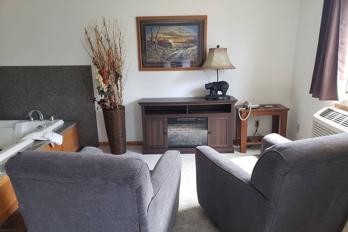 A living room with a sofa, a fireplace, a lamp, a painting, and a vase with branches.