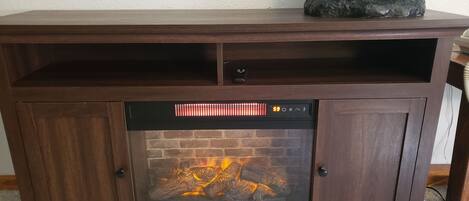 A fireplace with a digital control panel, a shelf above it, and a bear statue on the mantel.