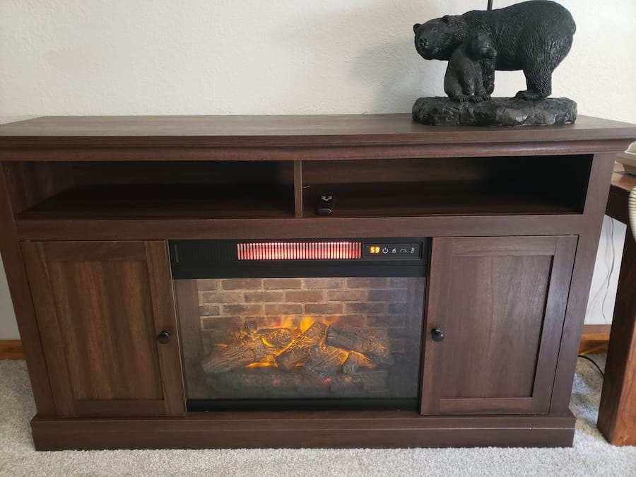 A fireplace with a digital control panel, a shelf above it, and a bear statue on the mantel.