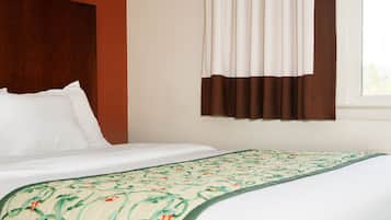 Cama bem arrumada com colcha estampada e cabeceira em frente a uma parede vermelha.