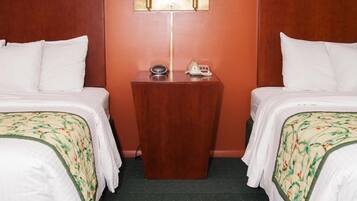 Una camera d'albergo con due letti, un comodino con lampada e un telefono.
