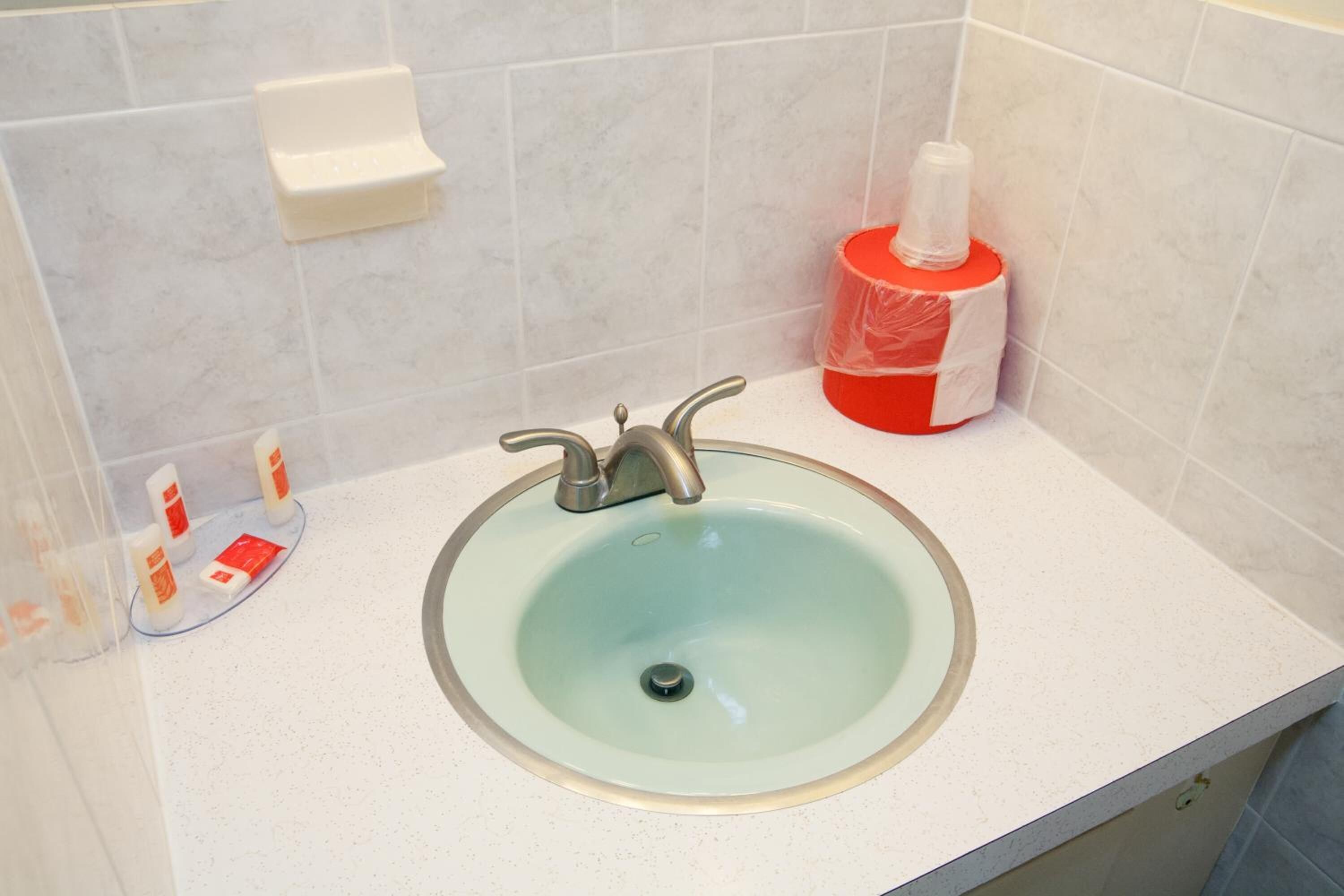 A bathroom with a light blue sink, a silver faucet, a soap dispenser, and a hand soap dispenser.