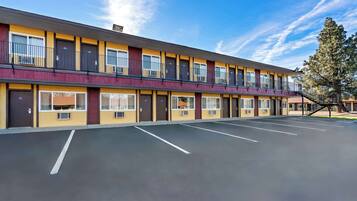 A multi-story motel with a parking lot in front.