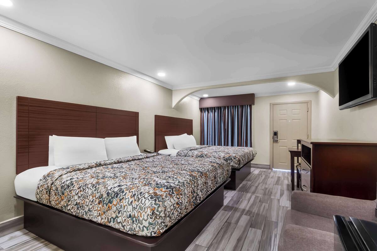 A hotel room with a large bed, a desk, and a TV.