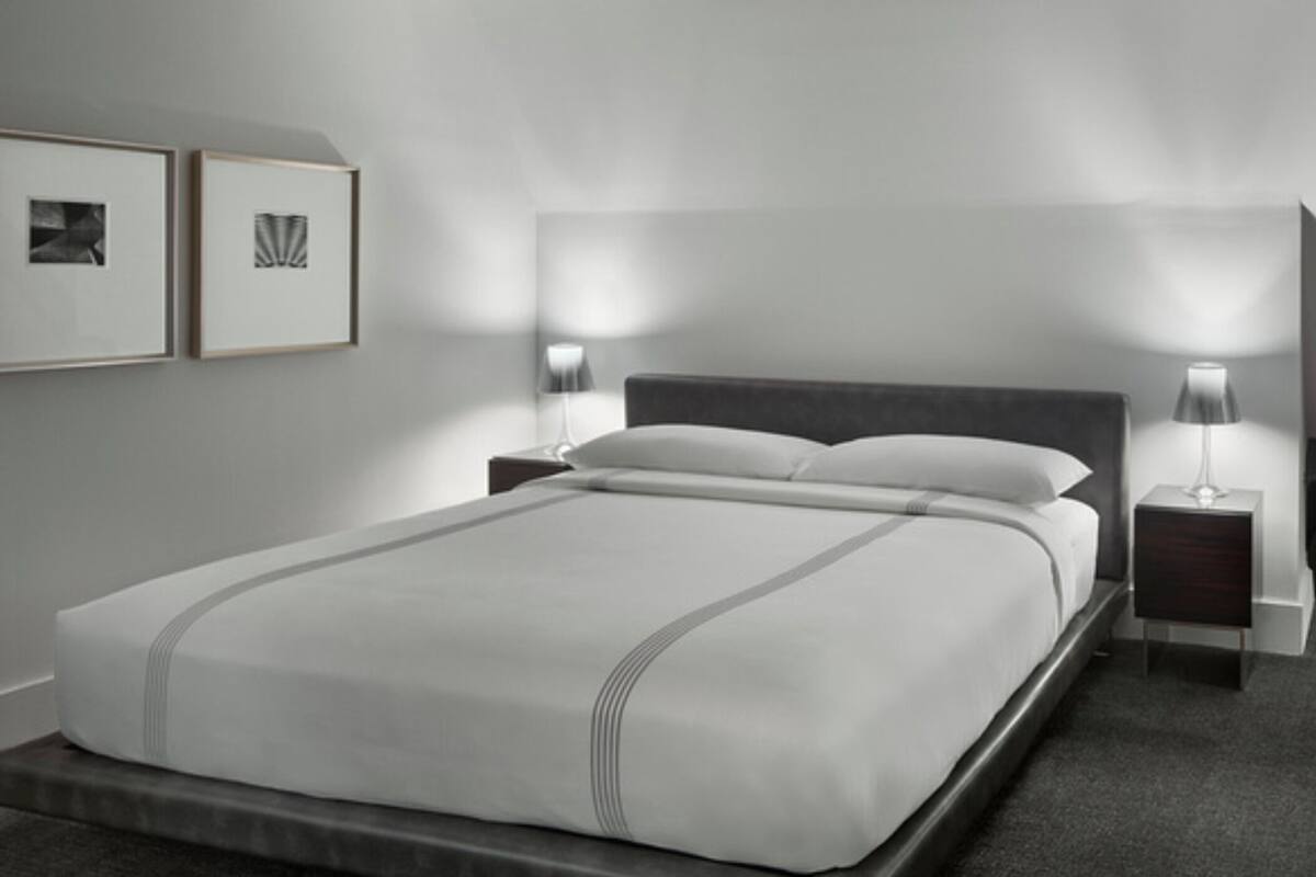 A modern bedroom with a large bed, two bedside tables, and two wall-mounted lamps.