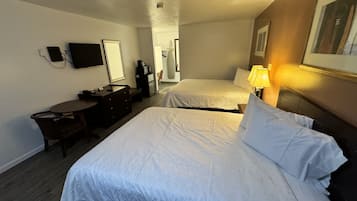 Ein Hotelzimmer mit zwei Betten, einem Schreibtisch, einem Sessel, einem Fernseher und einer Lampe.