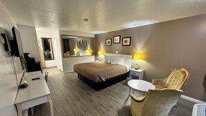 A hotel room with a bed, bedside lamps, a desk with a computer, a chair, and a mirror. - Inn Towne Motel (Herkimer)