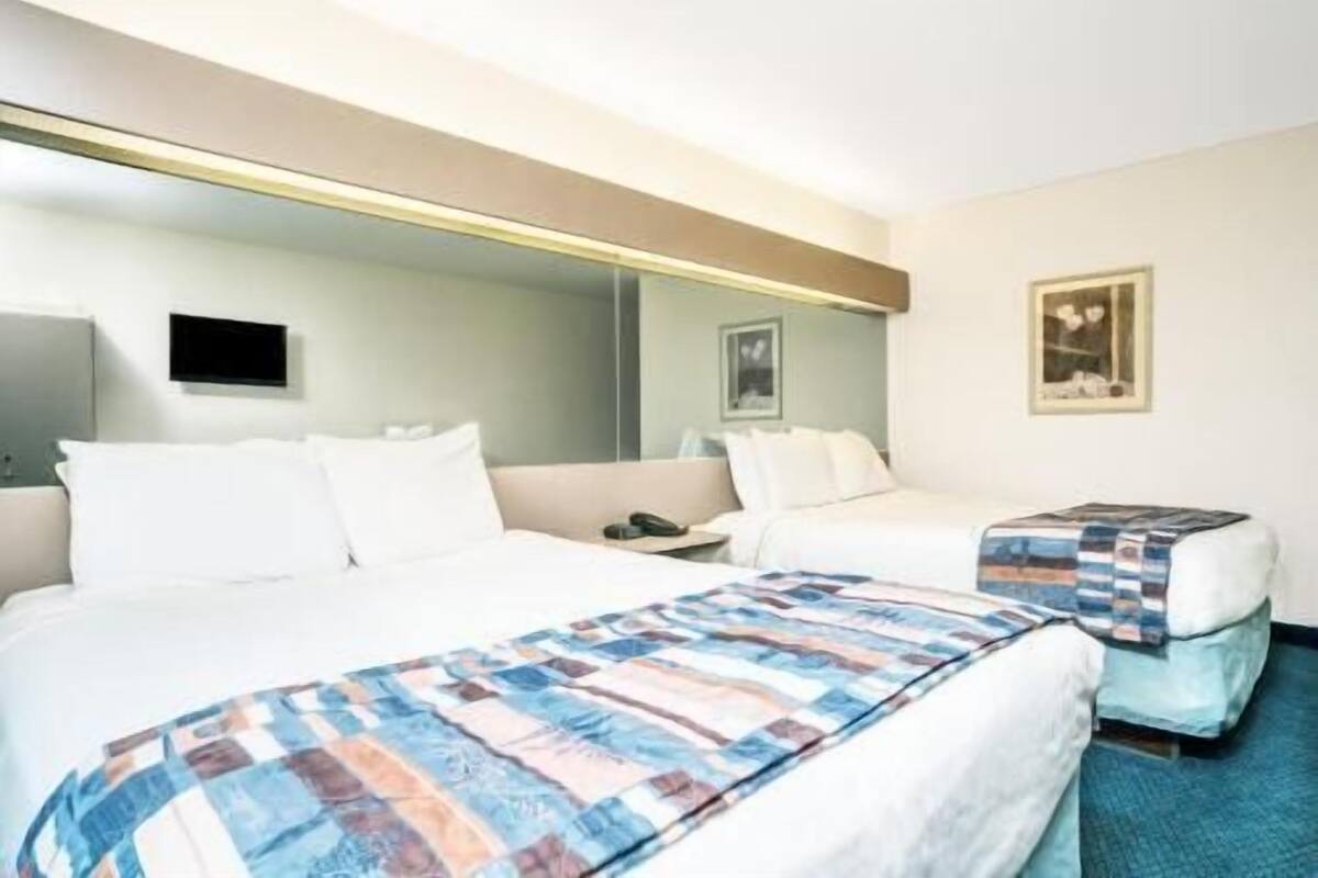 Een hotelkamer met een groot bed, een kleiner bed, een bureau en een spiegel.